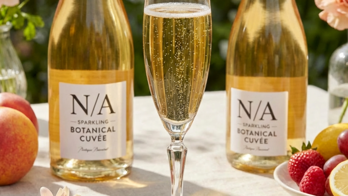 Sparkling non-alcoholic cuvée with raspberries and lemon twist in a sunlit garden.